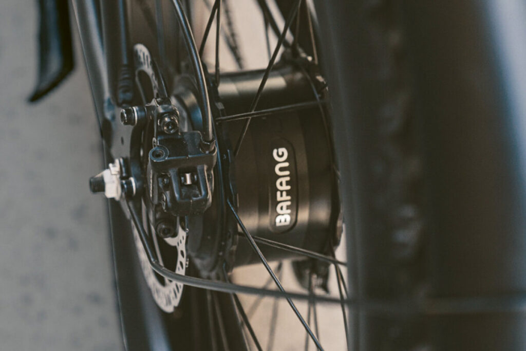 Detailaufnahme eines schwarzen E-Bikes mit dem Namen Max E-CoffeeCruiser. Nahaufnahme des Hinterradnabenmotors.