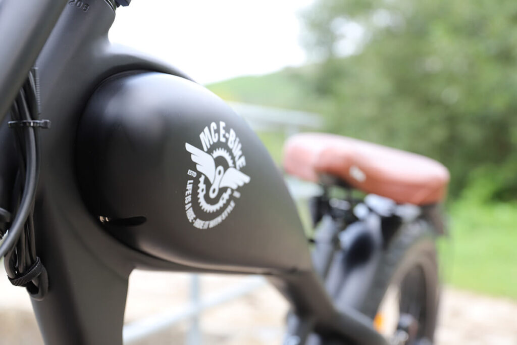 Detailaufnahme eines schwarzen E-Bikes mit dem Namen Max E-CoffeeCruiser. Nahaufnahme des E-Bike-Tanks.